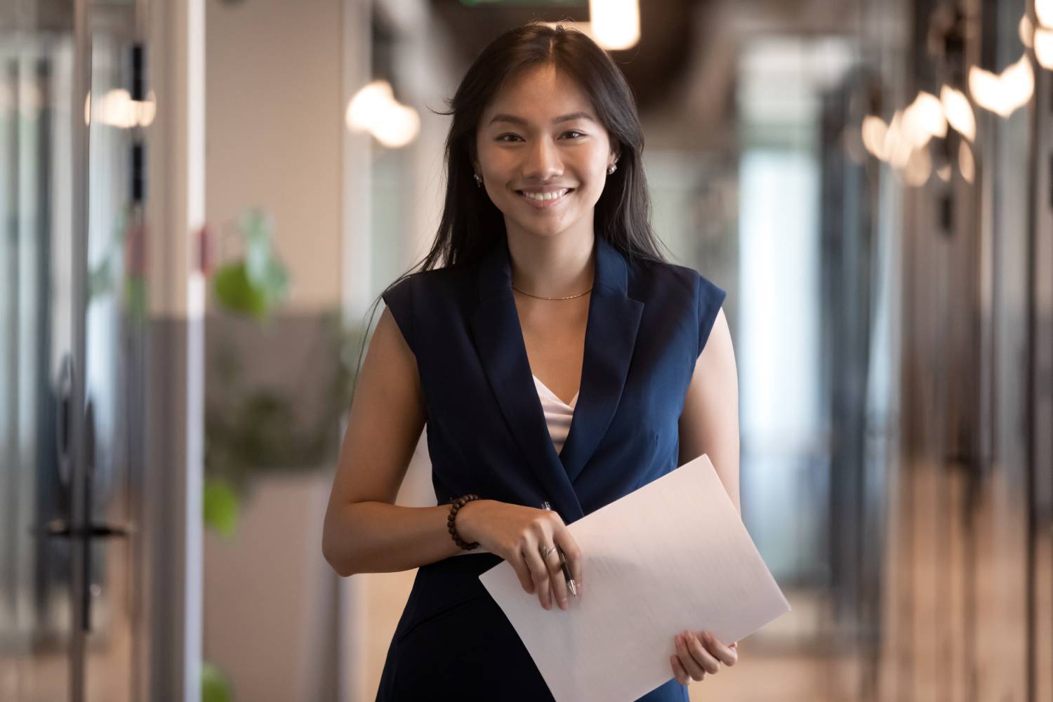 Happy smiling asian businesswoman looking at camera holding papers