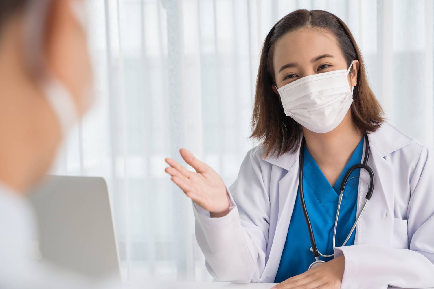 Patient visiting female doctor at clinic office doctor wear face mask